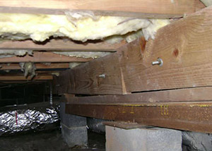 A sagging crawl space with concrete supports and wooden shimming a Monticello crawl space